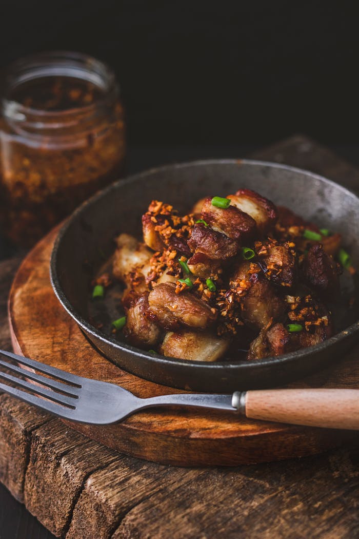 Delicious Filipino pork sisig garnished with crispy garlic and chives in a rustic setting.